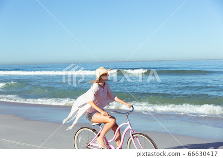 Caucasian woman spending time seaside and riding a bike 66630417