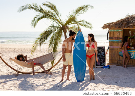 Mixed race people holding surf board on beach Mixed race people holding surf board on beach 66630493