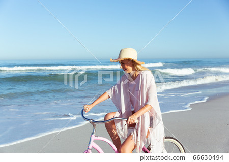 Caucasian woman spending time seaside and riding a bike Caucasian woman spending time seaside and riding a bike 66630494