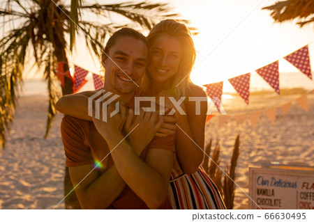 Caucasian friends hugging on beach 66630495