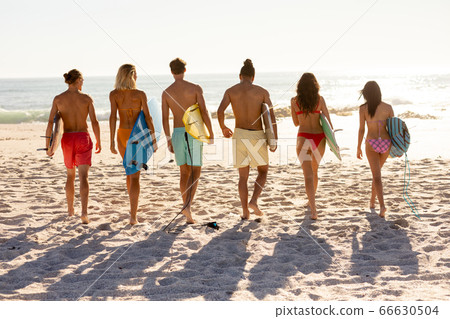 Young mixed race people holding surf boards on beach Young mixed race people holding surf boards on beach 66630504