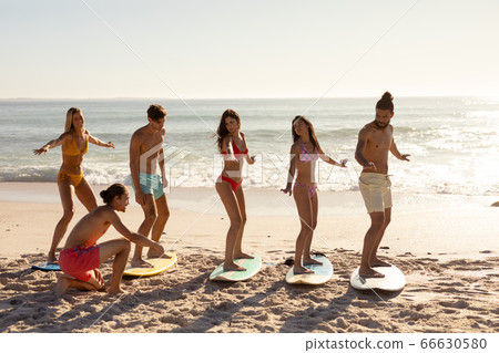 Multi-ethnic group of male and female, surfing on the beach Multi-ethnic group of male and female, surfing on the beach 66630580