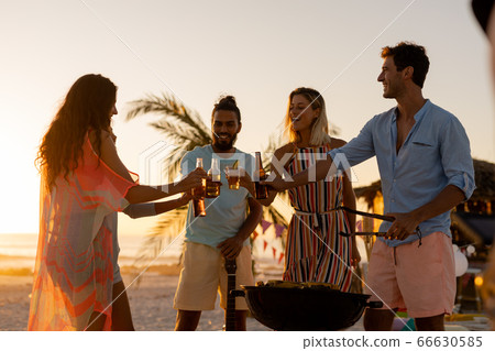 Mixed race friends doing barbecue and drinking alcohol on beach Mixed race friends doing barbecue and drinking alcohol on beach 66630585