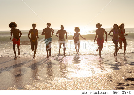 Multi-ethnic group of male and female standing on the beach Multi-ethnic group of male and female standing on the beach 66630588