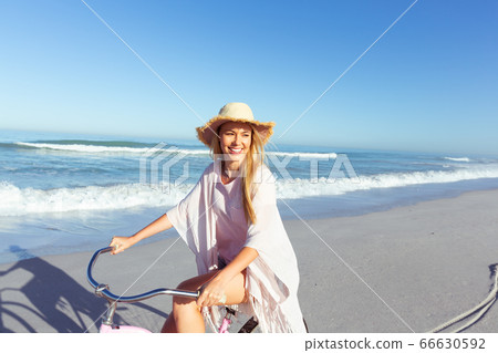Caucasian woman spending time seaside and riding a bike Caucasian woman spending time seaside and riding a bike 66630592