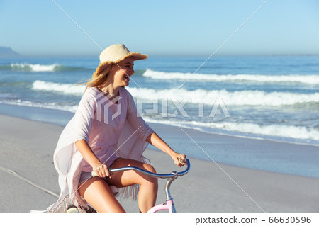 Caucasian woman spending time seaside and riding a bike 66630596
