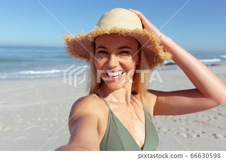 Caucasian woman using a phone and taking selfie at beach Caucasian woman using a phone and taking selfie at beach 66630598