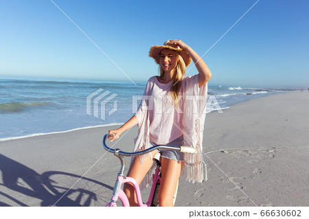 Caucasian woman spending time seaside and riding a bike Caucasian woman spending time seaside and riding a bike 66630602