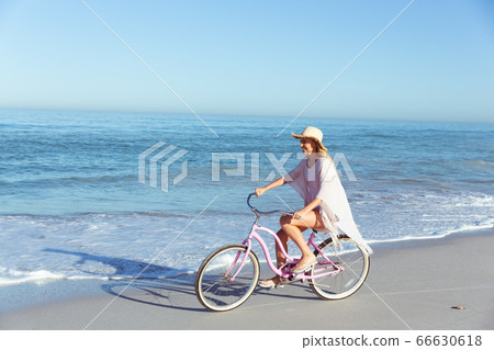 Caucasian woman spending time seaside and riding a bike 66630618