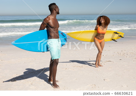 Happy couple holding surfboards on the beach Happy couple holding surfboards on the beach 66630621