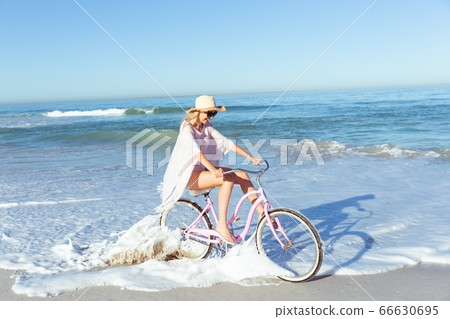 Caucasian woman spending time seaside and riding a bike Caucasian woman spending time seaside and riding a bike 66630695