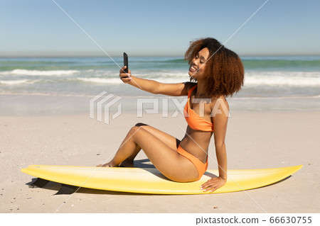 Mixed race woman taking a selfie on the beach 66630755