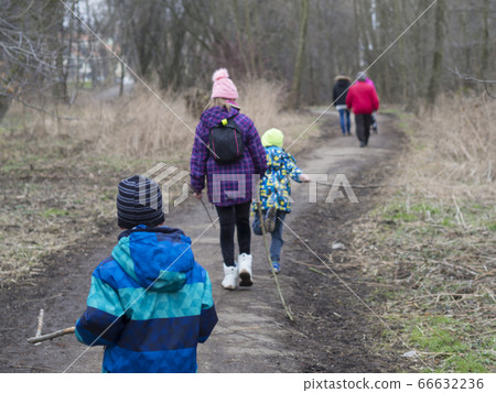three children in colorful jacket holding stick 66632236