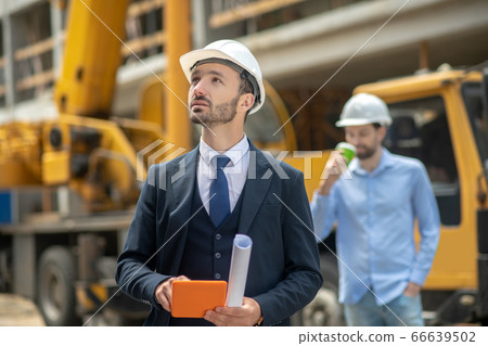Building supervisor holding tablet, foreman standing behind him drinking coffee 66639502