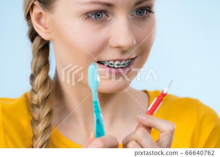 Woman smiling cleaning teeth with braces 66640762