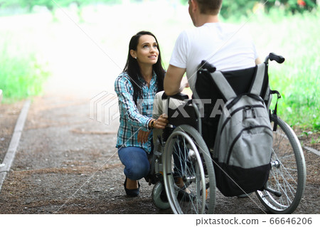 Disabled couple in love on a walk in park portrait. Wife looks at her husband in love with eyes Disabled couple in love on a walk in park portrait. Wife looks at her husband in love with eyes 66646206
