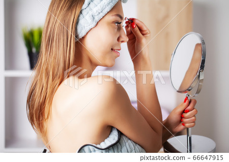 Beauty makeup, young woman with beautiful skin holding eyelash brush near eyes Beauty makeup, young woman with beautiful skin holding eyelash brush near eyes 66647915