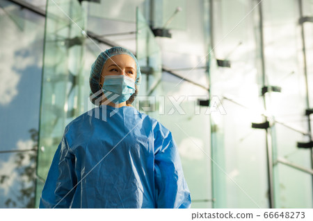 Confident female medical doctor or nurse in surgical mask and surgical cap looks at you Confident female medical doctor or nurse in surgical mask and surgical cap looks at you 66648273