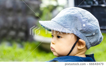 Side view of a child wearing a hat and green back 66648479