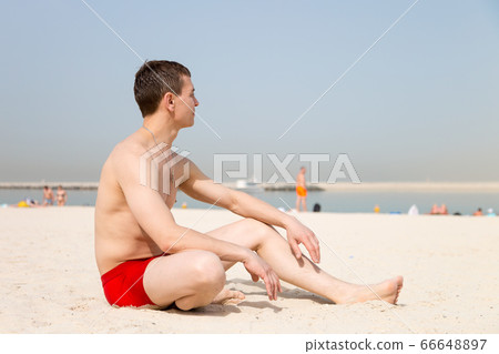 Resting Caucasian man sitting on the beach. Resting Caucasian man sitting on the beach. 66648897