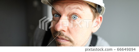 Surprised man in helmet looks closely and listens Surprised man in helmet looks closely and listens 66649894