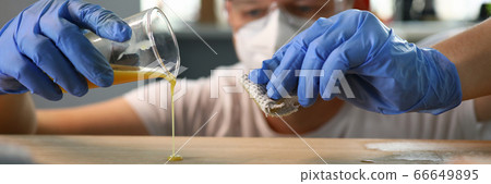 Carpenter pours varnish from glass wooden surface Carpenter pours varnish from glass wooden surface 66649895