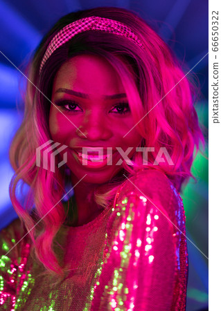 Sexy African woman smiles in pink neon glow. Close up portrait. Bright night makeup concept. Vogue concept 66650322