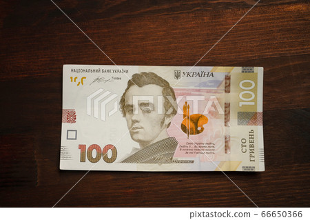 New Ukrainian money. Paper one hundred hryvnia notes with famous Ukrainian historical figure, artist and poet Taras Shevchenko on it. High angle view 66650366