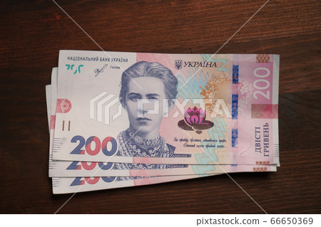 New Ukrainian paper money. Two hundred hryvnia notes on brown wooden background. Cash concept. Close up shot. High angle view 66650369