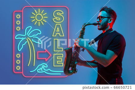 Young jazz musician playing the saxophone in neon light with neon sign 66650721