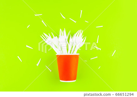 Broken plastic forks in a plastic cup instead of a bouquet of flowers on a green background. Broken plastic forks in a plastic cup instead of a bouquet of flowers on a green background. 66651294