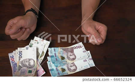 Male hands and pack of new money. Caucasian man with Ukrainian paper banknote, 200, 500 and 1000 hryvnias. Exchange concept. High angle view 66652324