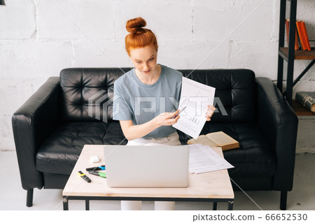 Professional redhead young business woman wearing wireless earphones is communicating by video call 66652530