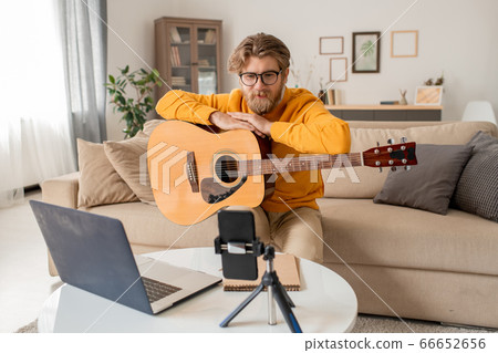 Young teacher talking to his audience during online lesson of playing guitar 66652656
