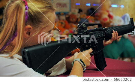 Girl teenager with a gun shoots at a shooting range. Girl teenager with a gun shoots at a shooting range. 66653202