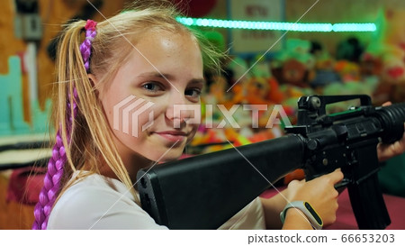 Girl teenager with a gun shoots at a shooting range. Girl teenager with a gun shoots at a shooting range. 66653203