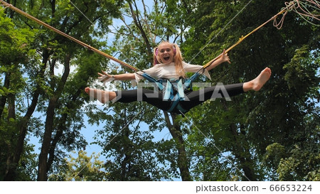 Teenage girl silhouette jumping on the trampoline bungee jumping. Teenage girl silhouette jumping on the trampoline bungee jumping. 66653224