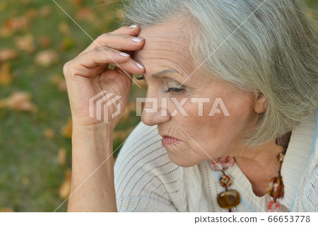 Portrait of sad, thoughtful senior woman in park 66653778