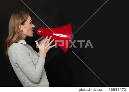 Angry woman shouting with loudspeaker megaphone 66653970