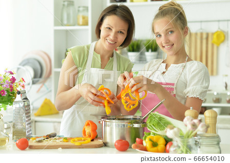 Portrait of cute little girl with mother cooking 66654010