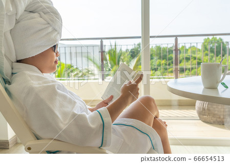 Side view of Asian woman relax on chair and reading book  66654513