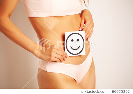 Stomach health and good digestion concepts, close up of healthy woman with beautiful fit slim body holding card with happy smile in hands. 66655202