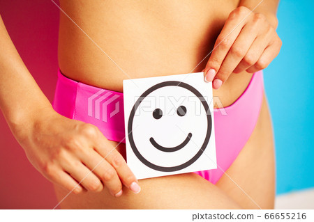 Stomach health and good digestion concepts, close up of healthy woman with beautiful fit slim body in pink panties holding card with happy smile in hands. 66655216