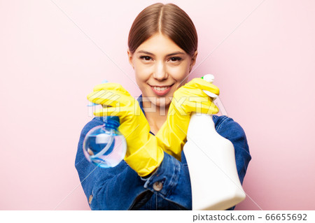 Woman cleaner in overalls and yellow gloves posing on a pink background Woman cleaner in overalls and yellow gloves posing on a pink background 66655692