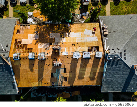 A worker replace shingles on the roof of a home 66656069