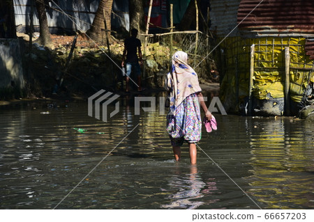 Cox's Bazar in Bangladesh A Muslim woman walking on a flooded road Wearing an Islamic hijab 66657203