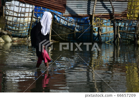 Cox's Bazar in Bangladesh Female student walking on flooded road to school wearing Islamic hijab Cox's Bazar in Bangladesh Female student walking on flooded road to school wearing Islamic hijab 66657209