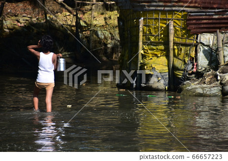Cox's Bazar in Bangladesh A child walking on a flooded road carrying a metal container Cox's Bazar in Bangladesh A child walking on a flooded road carrying a metal container 66657223
