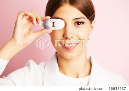 The ophthalmologist holds a container with contact lenses near the eyes 66658387