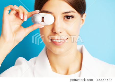 The ophthalmologist holds a container with contact lenses near the eyes The ophthalmologist holds a container with contact lenses near the eyes 66658388